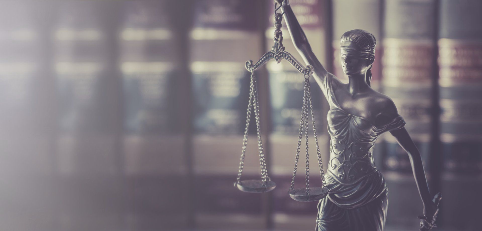 Eine Justicia-Figur steht auf einem Tisch vor einem Bücherregal.