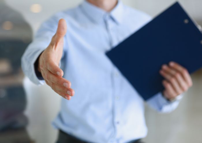 Ein Mann hält eine Akte fest und streckt die Hand aus